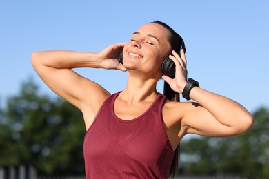Photo of Athletic young woman with headphones in sportswear before running outdoors