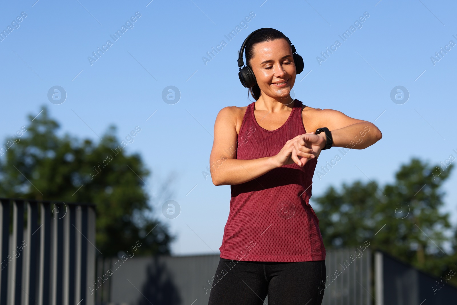 Athletic young woman with headphones checking fitness tracker before running outdoors, space for text Photo of Athletic young woman with headphones checking fitness tracker before running outdoors, space for text