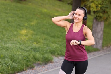 Photo of Athletic young woman with headphones in sportswear before running outdoors, space for text