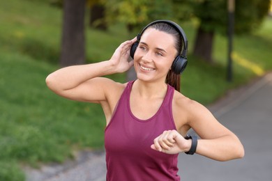 Photo of Athletic young woman with headphones in sportswear before running outdoors