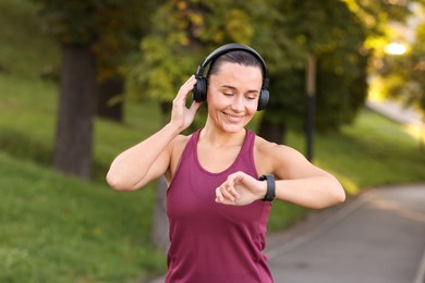 Photo of Athletic young woman with headphones in sportswear before running outdoors