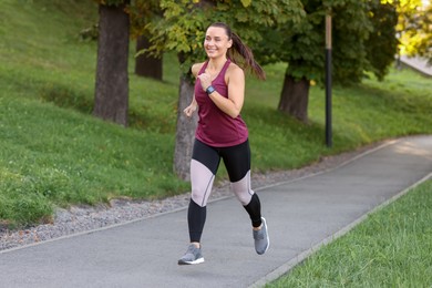 Photo of Athletic young woman in sportswear running outdoors