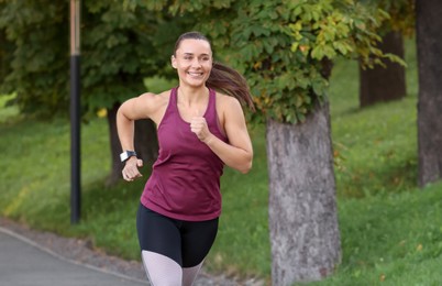 Photo of Athletic young woman in sportswear running outdoors, space for text