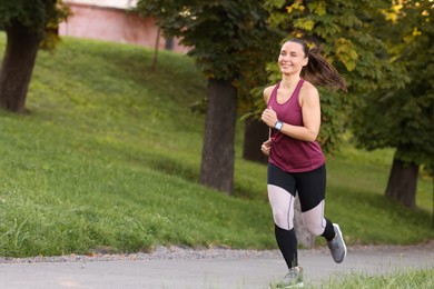 Photo of Athletic young woman in sportswear running outdoors, space for text