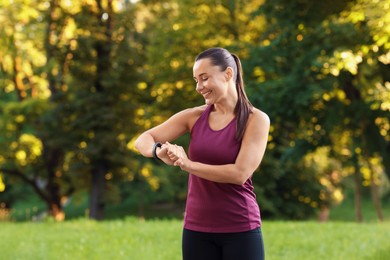 Photo of Athletic young woman checking fitness tracker before running outdoors
