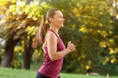 Photo of Athletic young woman in sportswear running outdoors