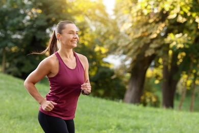 Photo of Athletic young woman in sportswear running outdoors, space for text