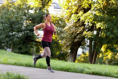 Photo of Athletic young woman in sportswear running outdoors, space for text