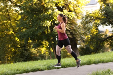 Photo of Athletic young woman in sportswear running outdoors
