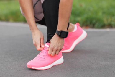 Photo of Woman tying shoelaces before running outdoors, closeup