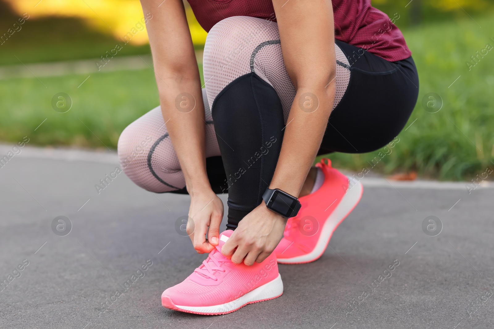 Woman tying shoelaces before running outdoors, closeup Photo of Woman tying shoelaces before running outdoors, closeup