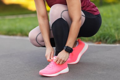 Photo of Woman tying shoelaces before running outdoors, closeup