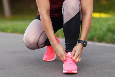 Photo of Woman tying shoelaces before running outdoors, closeup