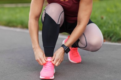 Photo of Woman tying shoelaces before running outdoors, closeup