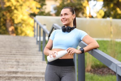 Photo of Athletic young woman with headphones in sportswear before running outdoors
