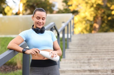 Photo of Athletic young woman with headphones in sportswear before running outdoors, space for text