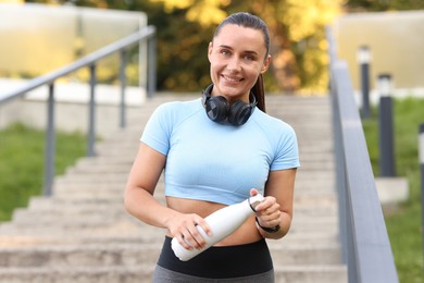 Photo of Athletic young woman with headphones in sportswear before running outdoors