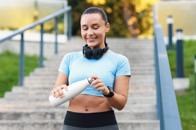 Photo of Athletic young woman with headphones in sportswear before running outdoors