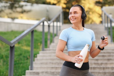 Photo of Athletic young woman with headphones in sportswear before running outdoors, space for text