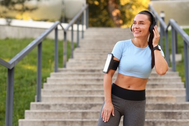 Photo of Athletic young woman with headphones in sportswear before running outdoors, space for text