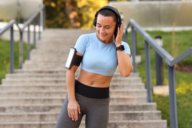 Photo of Athletic young woman with headphones in sportswear before running outdoors
