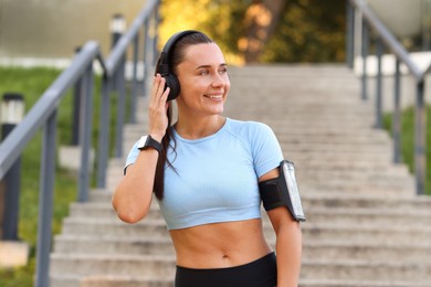 Photo of Athletic young woman with headphones in sportswear before running outdoors