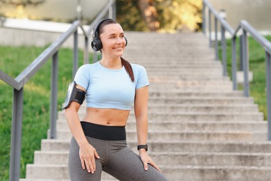 Photo of Athletic young woman with headphones in sportswear before running outdoors, space for text