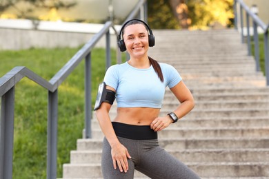 Photo of Athletic young woman with headphones in sportswear before running outdoors