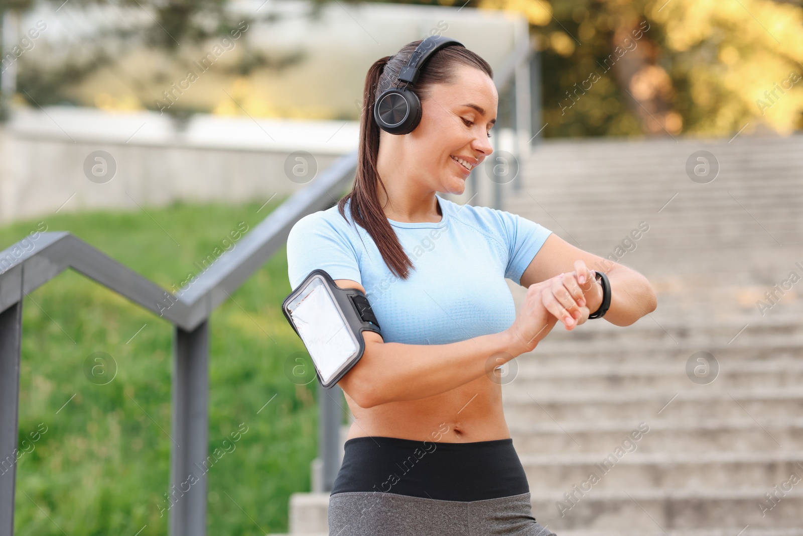Athletic young woman with headphones checking fitness tracker before running outdoors Photo of Athletic young woman with headphones checking fitness tracker before running outdoors