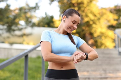 Photo of Athletic young woman checking fitness tracker before running outdoors