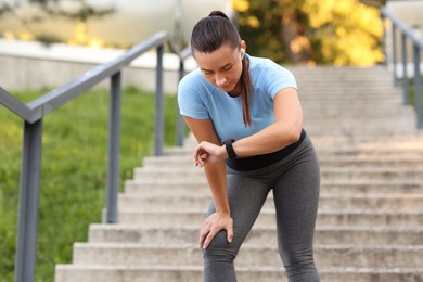 Photo of Athletic young woman checking fitness tracker before running outdoors