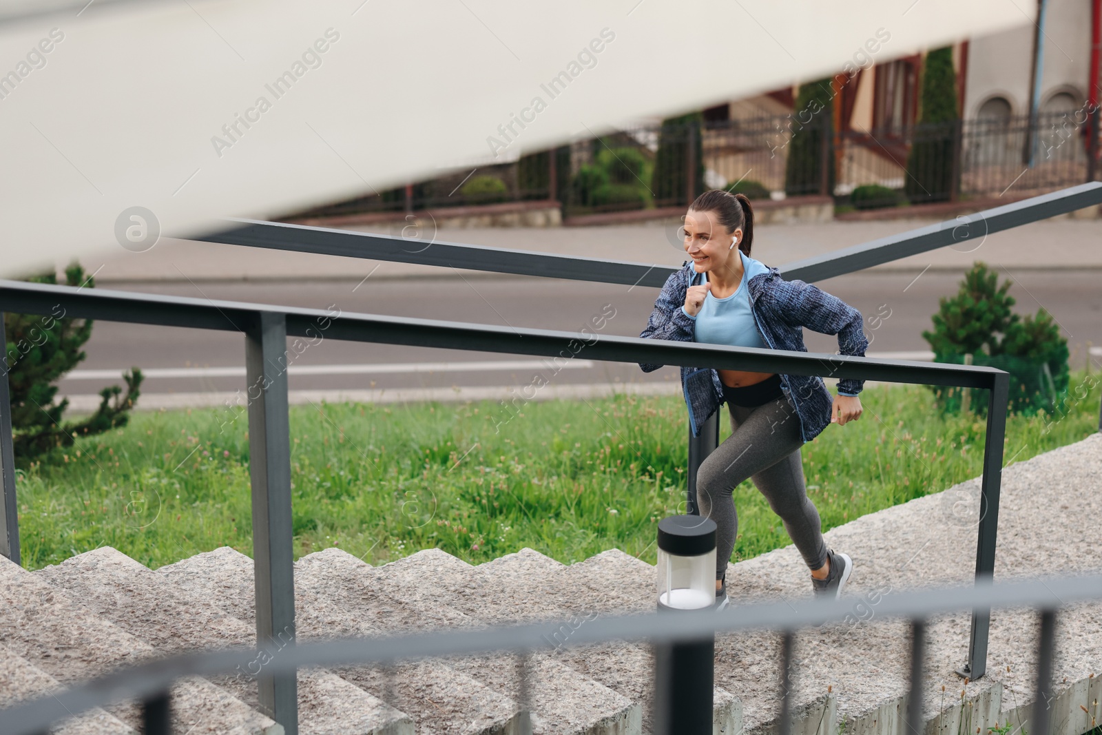 Woman in sportswear running up on stairs outdoors, space for text Photo of Woman in sportswear running up on stairs outdoors, space for text