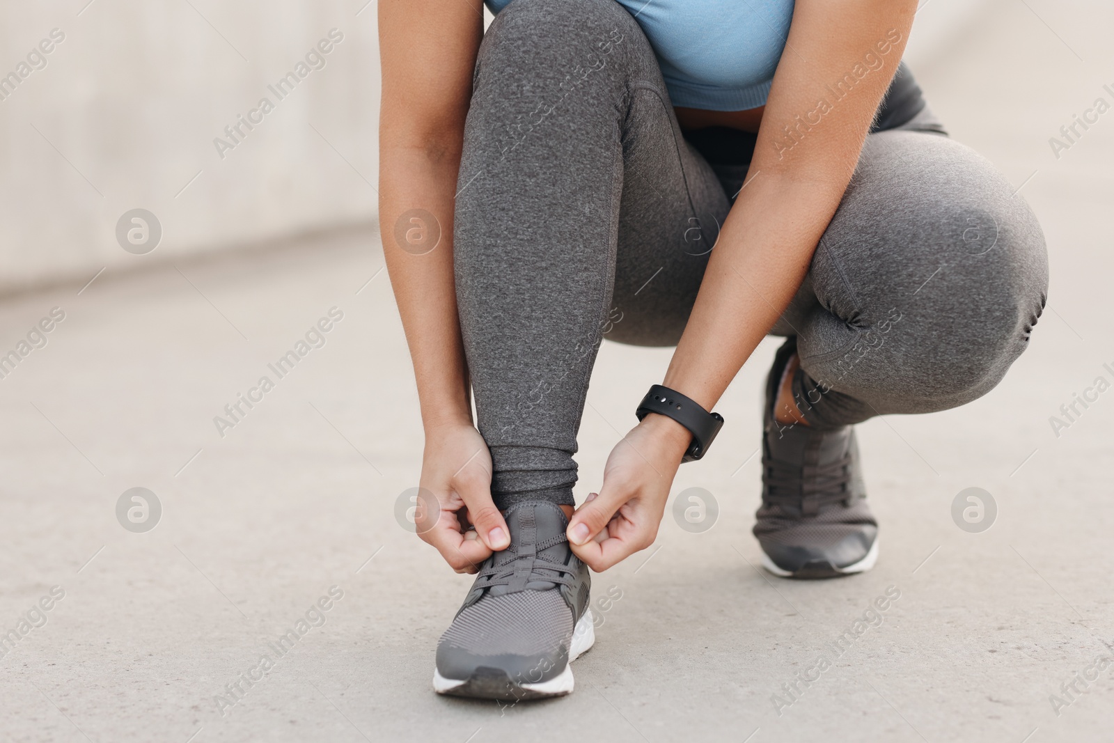 Woman tying shoelaces before running outdoors, closeup Photo of Woman tying shoelaces before running outdoors, closeup