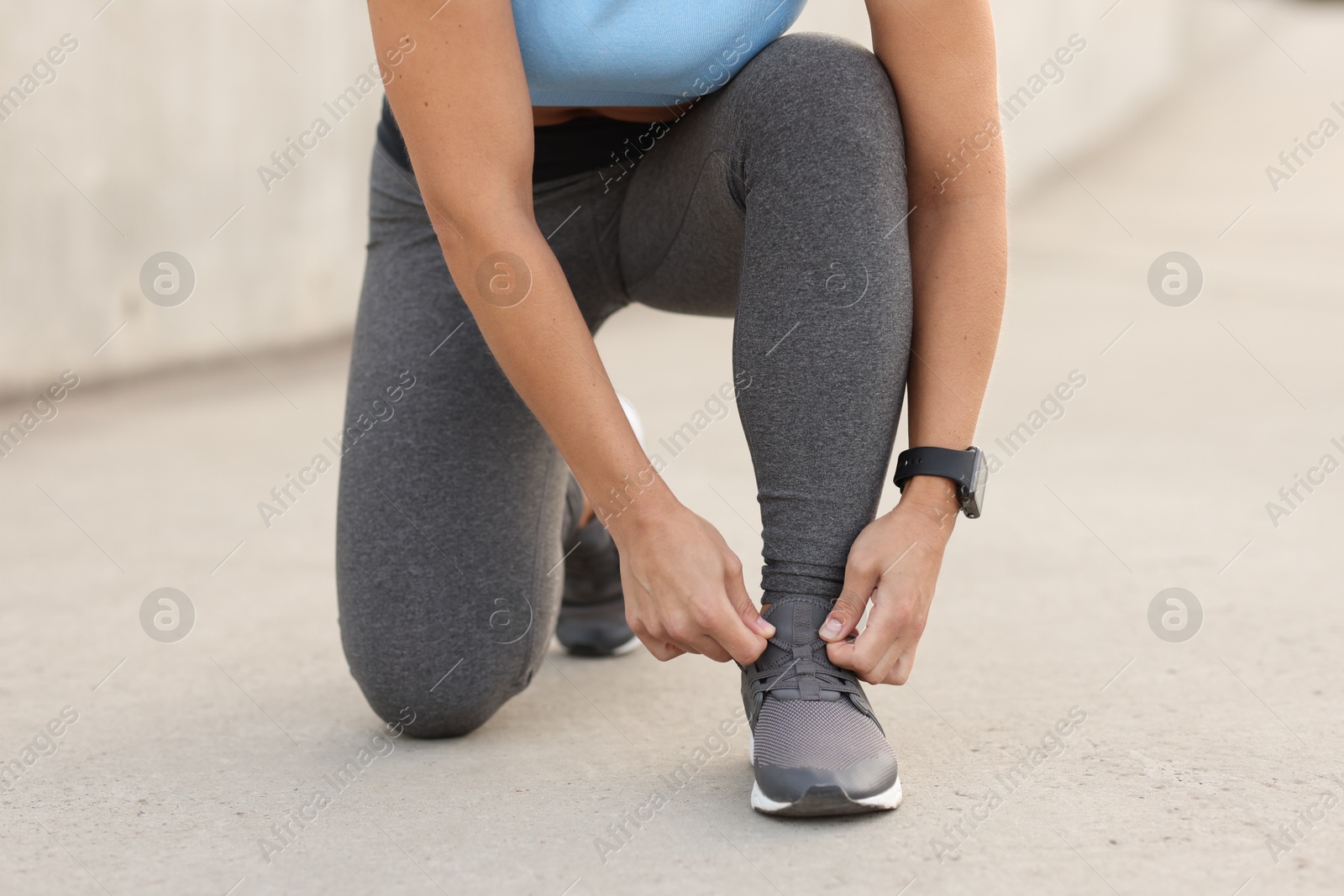 Woman tying shoelaces before running outdoors, closeup Photo of Woman tying shoelaces before running outdoors, closeup