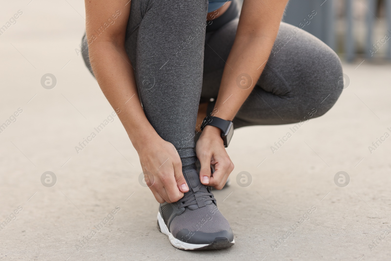Woman tying shoelaces before running outdoors, closeup Photo of Woman tying shoelaces before running outdoors, closeup
