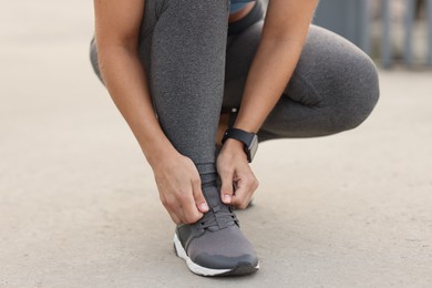 Photo of Woman tying shoelaces before running outdoors, closeup