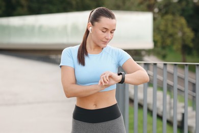 Photo of Athletic young woman checking fitness tracker before running outdoors
