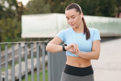 Photo of Athletic young woman checking fitness tracker before running outdoors