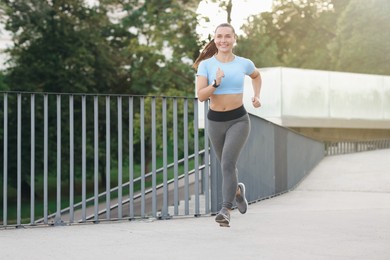 Photo of Athletic young woman in sportswear running outdoors