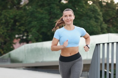 Photo of Athletic young woman in sportswear running outdoors, space for text