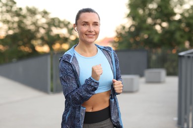 Photo of Athletic young woman in sportswear running outdoors