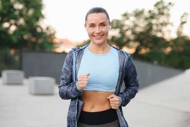 Photo of Athletic young woman in sportswear running outdoors