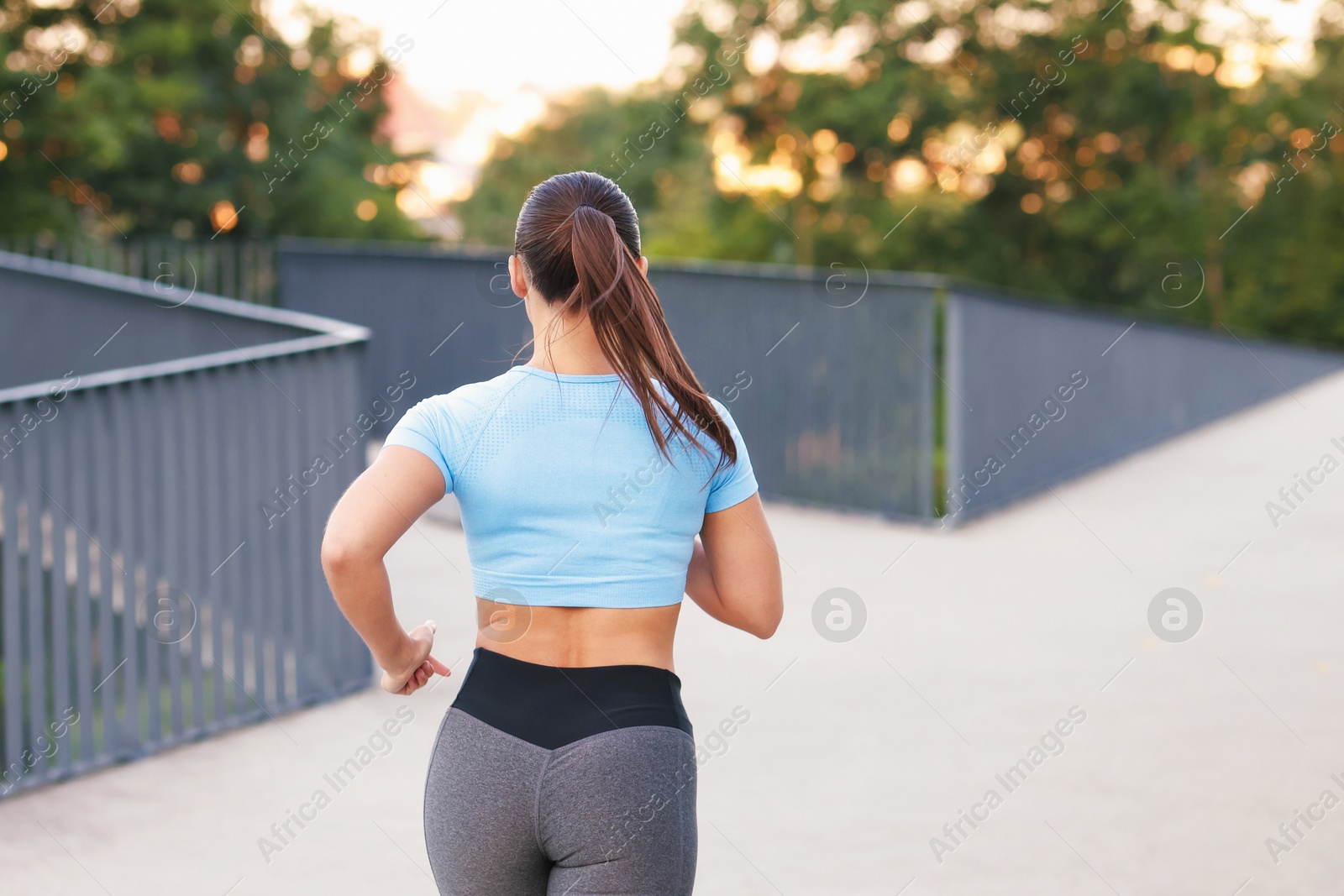 Young woman in sportswear running outdoors, back view. Space for text Photo of Young woman in sportswear running outdoors, back view. Space for text