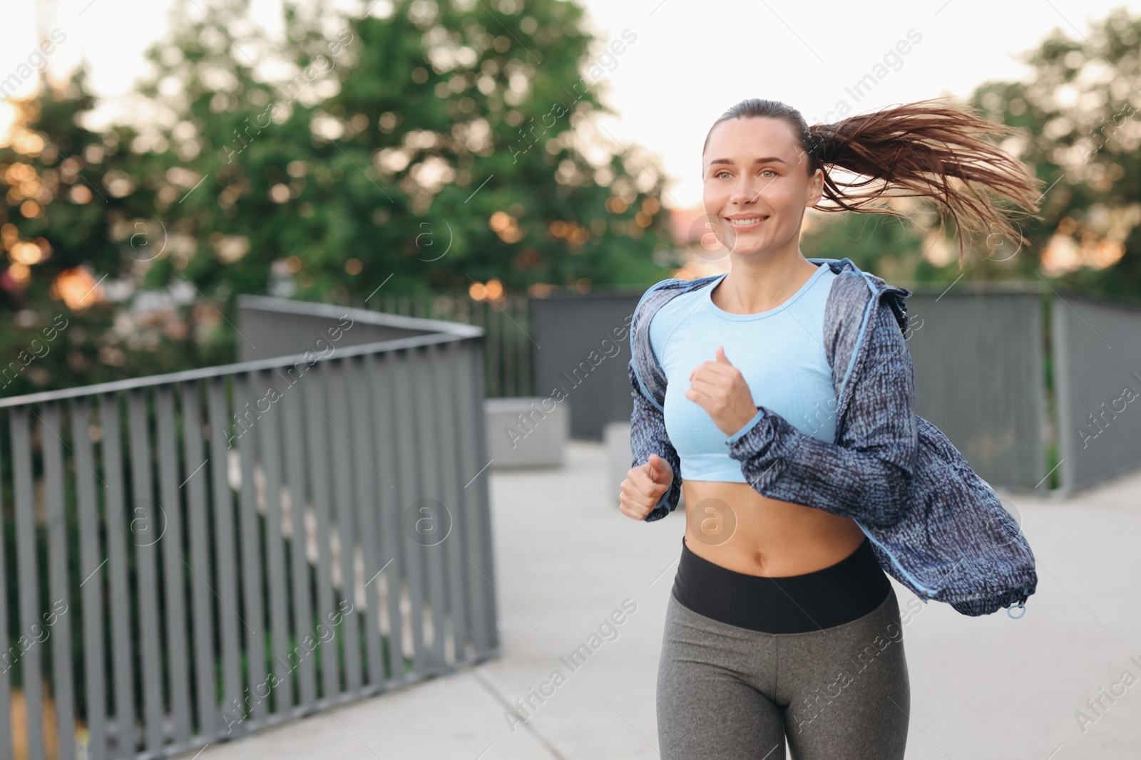Young woman in sportswear running outdoors, space for text Photo of Young woman in sportswear running outdoors, space for text