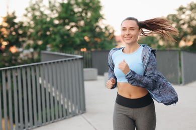 Photo of Young woman in sportswear running outdoors, space for text