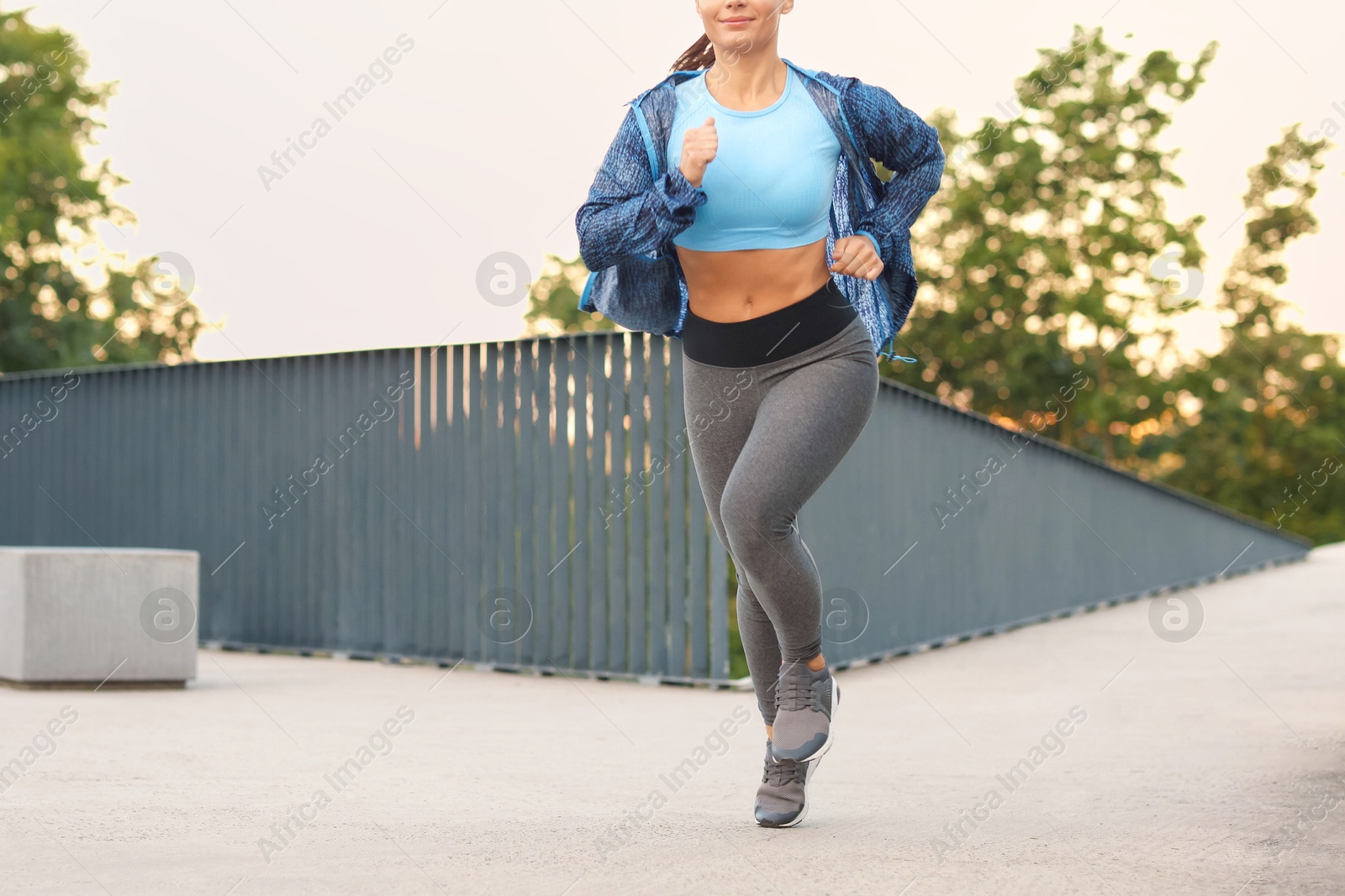 Young woman in sportswear running outdoors, closeup Photo of Young woman in sportswear running outdoors, closeup