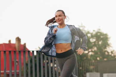Photo of Athletic young woman in sportswear running outdoors