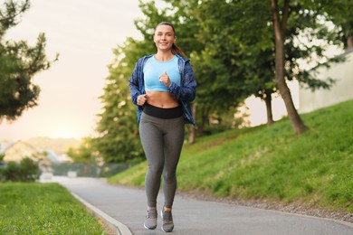 Photo of Athletic young woman in sportswear running outdoors
