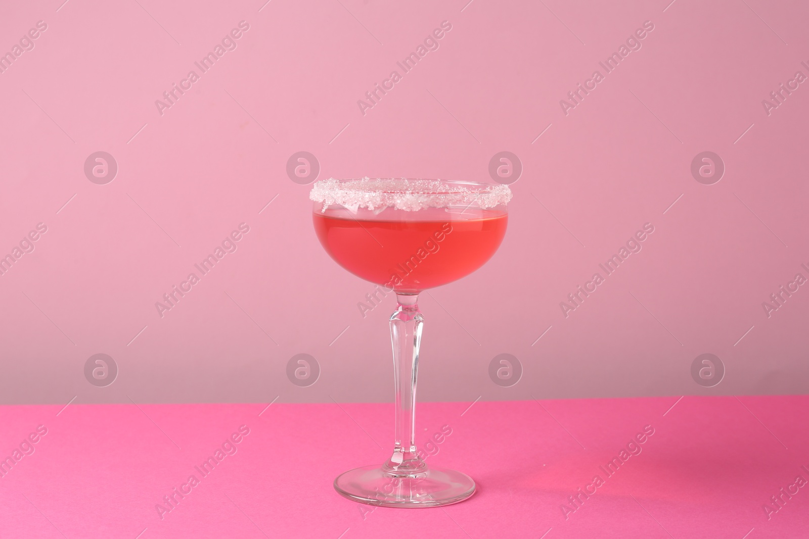 Martini cocktail with sugar in glass on pink background Photo of Martini cocktail with sugar in glass on pink background
