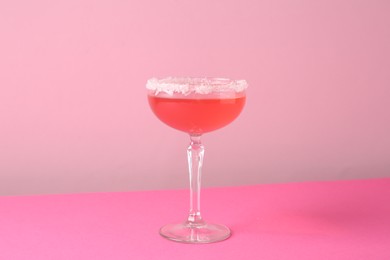 Photo of Martini cocktail with sugar in glass on pink background